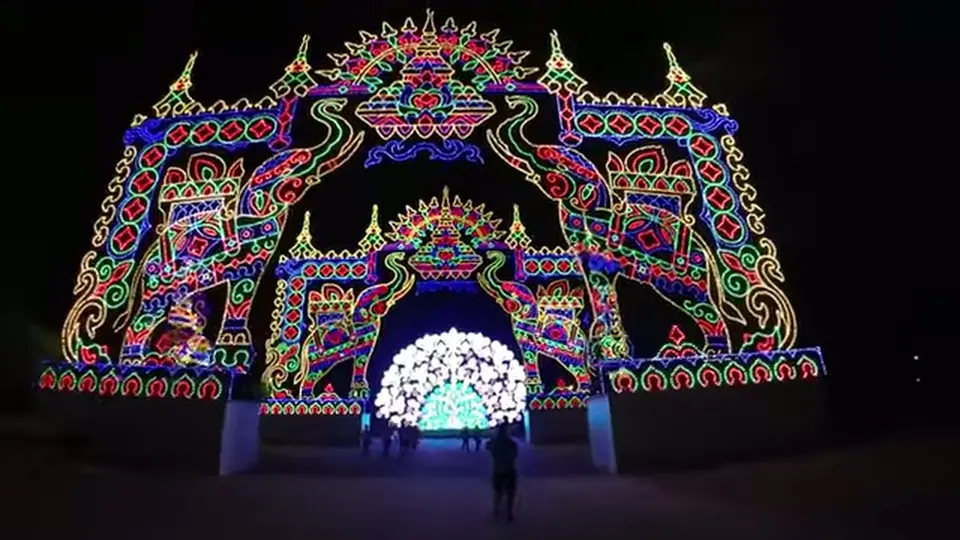 Illuminated elephant arch frames a bright nighttime light display.