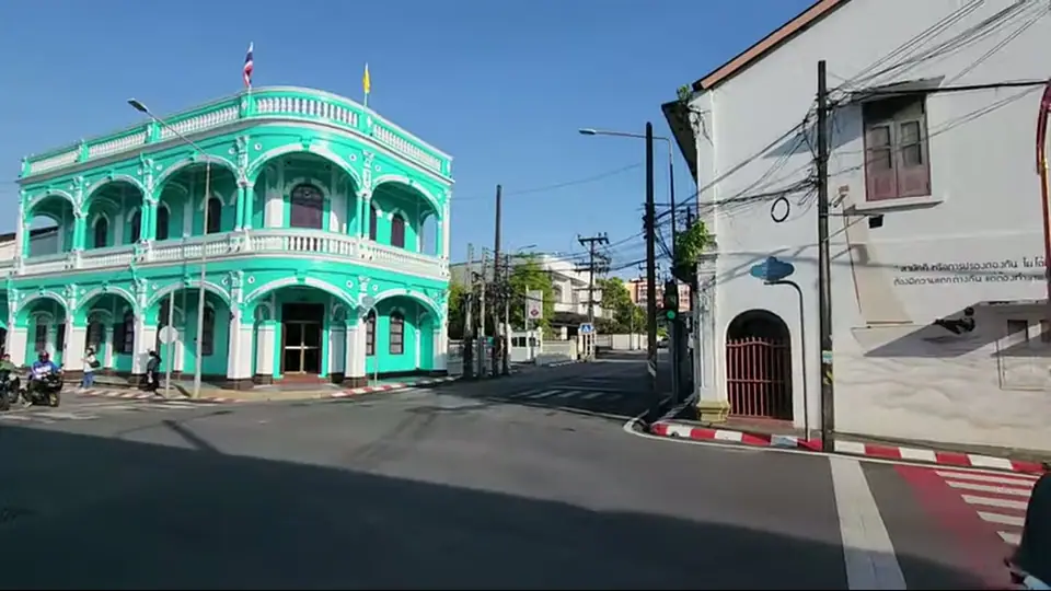 Turquoise Sino-Portuguese building with arches stands at an intersection.