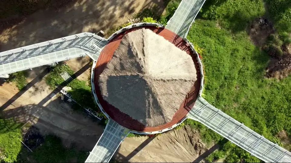 Circular thatched platform connects to elevated walkways over greenery.